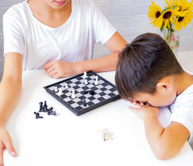 Children Play Chess at the Table, Boy Lost and Upset. Black White Chess Board