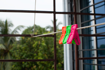 A trio of colourful plastic clothes pegs hanging on a washing line with blurred background	