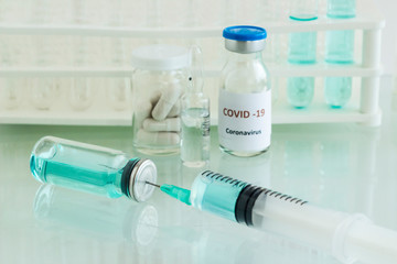 Mini medicine glass bottle and injector with medical materials on the glass table.Vaccine works in the laboratory.Selective focus