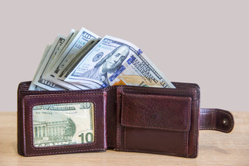 A wallet with American dollars lies on the table near the computer while a medical mask from viruses lies nearby. Virus mask protects a wallet with money in the office.