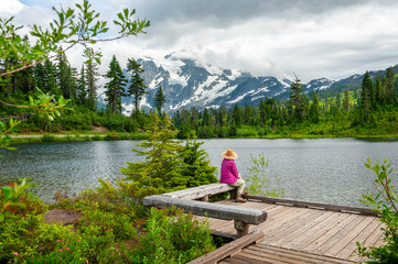 Senior Woman Admiring the View at Picture Lake, Washington. With Mt. Shuksan in the background, a senior woman rests at the viewing deck after hiking the path around the lake at Mt. Baker, Washington.
