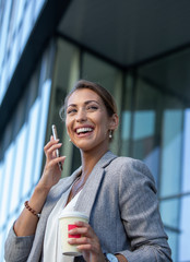 Business woman talking on phone and drinking coffee outdoor