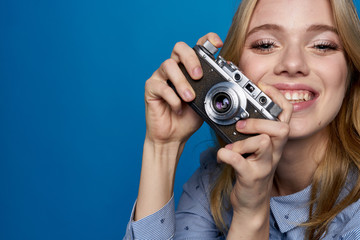 Beautiful blonde woman holding a camera smiling close-up cropped view