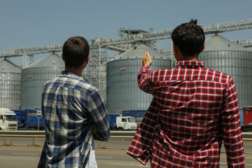 Two farmers against grain silos. Agriculture business