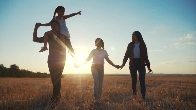 people in the park. happy family silhouette walk at sunset. mom dad and daughters walk holding hands in the park. happy family kid dream concept fun. parents and children walking back silhouette