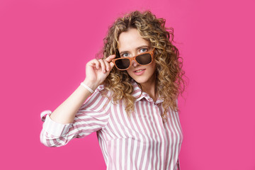 Portrait of a young, beautiful, healthy woman holding glasses and looking at the camera.