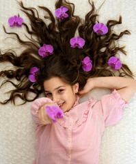 a portrait of a girl with long brown hair and a purple orchid