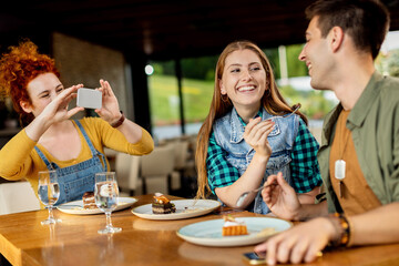 Young carefree friends having fun while eating dessert in a cafe.