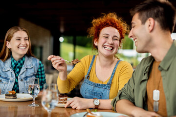 Group of happy friends having fun while eating cake in a cafe.