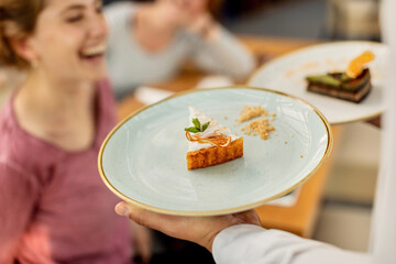 Close-up of waiter serving dessert to customers in a cafe.