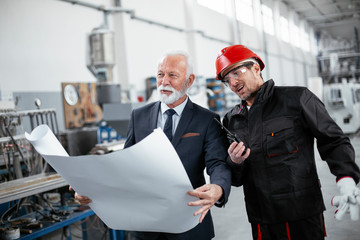 Colleagues working together. Arhitect and worker in factory.