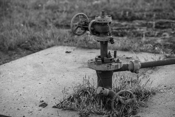 Oil pipes and valves in an oil field. Black and white photo