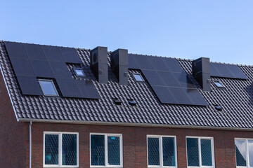 Solar panels on the tiled roofs of new buildings against the blue sky.