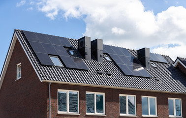 Solar panels on the tiled roofs of new buildings against the blue sky.