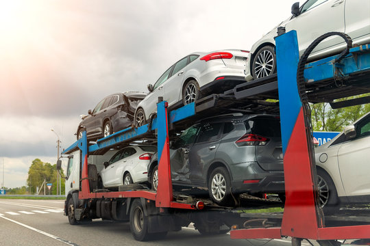 Tow truck car carrier semi trailer on highway carrying batch of damaged cars sold on insurance car auctions for repair and recovery. Vehicles shipment and rescue service