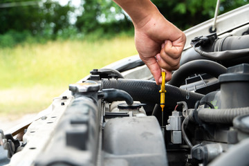 close up man checking the oil level in car engine