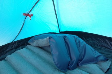 Interior of a tent with folded and partly deflated mattress during a sunny day
