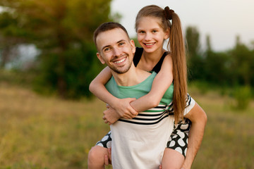 Obraz premium Beautiful little girl hugging embracing her father in summer