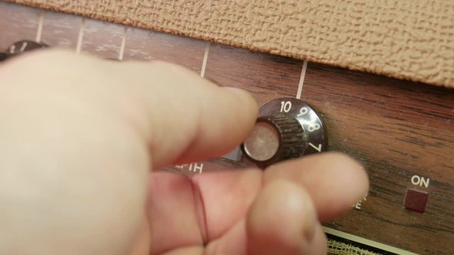 Vintage guitar amplifier knobs up close.  Dusty reverb and chorus dials being turned by hand.  Caucasian male hand turning the knobs multiple times.
