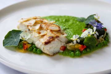 White fish fillet with potato scale, pea puree and summer vegetable