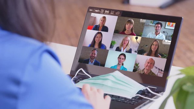 Online Group Video Call Conference of Work Team from Home Office. Asian Woman listens to 9 People at Video Chat using Laptop. Self-isolation at COVID-19 Pandemic
