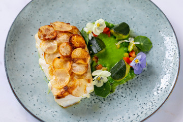 White fish fillet with potato scale, pea puree and summer vegetable