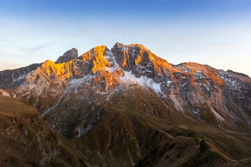 Italian Dolomites - view of the snow-capped peaks of the Dolomites, which are illuminated by the setting sun with a beautiful blue sky.