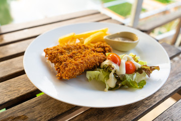 Dish Fish in batter with french fries. Fish on a plate with potatoes and salad in a summer cafe.