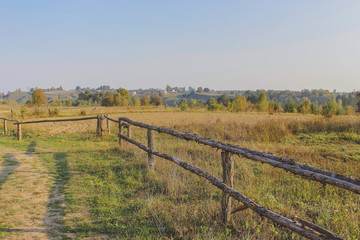 Fototapeta premium path in the field. wooden rustic fence