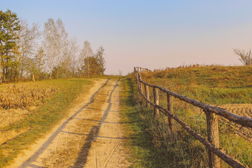 Fototapeta na wymiar path in the field. wooden rustic fence