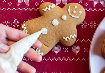 Boy is decorating  gingerbread cookies with icing sugar. Snowflake, star  shapes. 