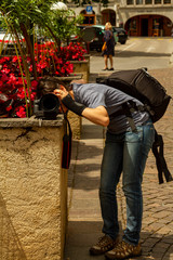 A photographer who does not have a tripod has put her camera on a wall and supported with bags to...