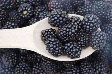 Plate of ripe blackberries on white wooden background