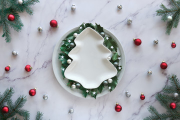 Christmas flat lay on marble table, copy-space on ceramic plate. Xmas background in green, white...