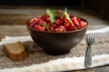 Vegetable salad, vinaigrette, in a ceramic earthenware, a folkloric bowl with a kitchen napkin on a wooden table. Village life. Home cooking.
