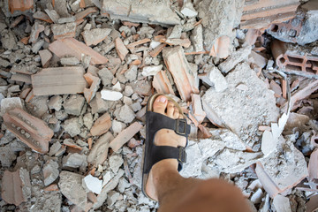 male feet in sandals over pile of building trash