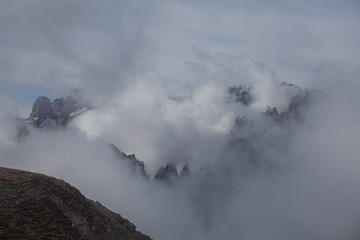 Sunrise over the Dolomite peaks half hidden by clouds and fog, Atmosphere of tranquility, relaxation and meditation