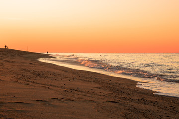 Fototapeta na wymiar Orange sunset over a sandy beach in autumn. Cape Cod, MA, USA.