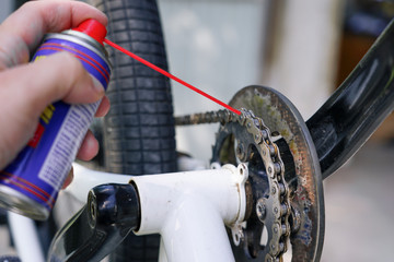 guy holding spray lubricant in his hand to lubricate the bike chain