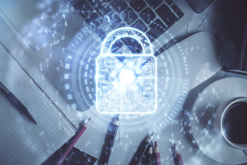 Double exposure of lock hologram drawing over study table background with computer. Concept of data security. Top view.