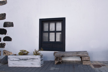 Facade of old house with window and rustic wooden bench in the town of Teguise