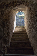 The view of exit door at the end of a dark ancient corridor in castle or mansion.