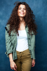 Fototapeta premium young pretty woman with curly brunette hair posing cheerful on blue background, lifestyle people concept