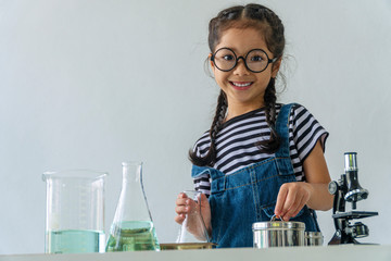 Little 6s cute girl with microscope holding laboratory bottle with water experiment study...