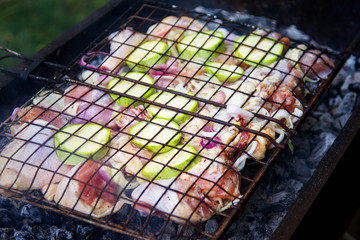 Meat and fresh vegetables on a metal grate to cook on coals. Cookout Concept.
