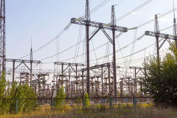 Power lines. High voltage power pylons against blue sky and sun rays