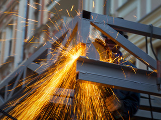 Close-up of worker cutting metal with grinder. Sparks while grinding iron. Low depth of focus