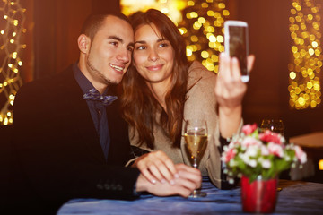 Young couple on romantic dinner taking selfie portrait photo with smartphone camera