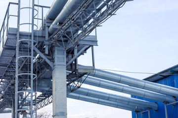 Naklejka premium Fragment Metal grain elevator in agricultural zone. Agricultural Silos. Building Exterior. Storage and drying of grains, wheat, corn, soy, sunflower on background of cloudy sky. Agriculture.