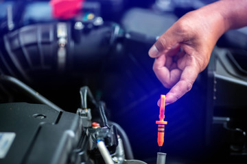 Selective focus to hand is checking the oil level in car engine.  Mechanic checking car engine or vehicle. Check and maintenance car with yourself. Service and maintenance vehicle.